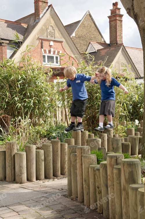 Preview: School boy and girl balancing on log fence
