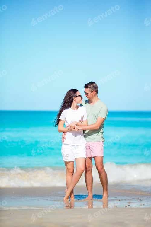 Vista previa: Young couple walking on tropical beach with white sand and turquoise ocean water at Antigua island