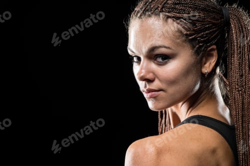 Preview: Portrait of a beautiful young sportswoman with dreadlocks on a black background