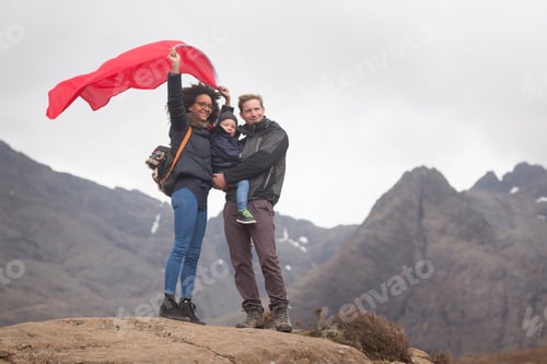 Preview: Family holding red flag in mountains, Fairy Pools, Isle of Skye, Hebrides, Scotland