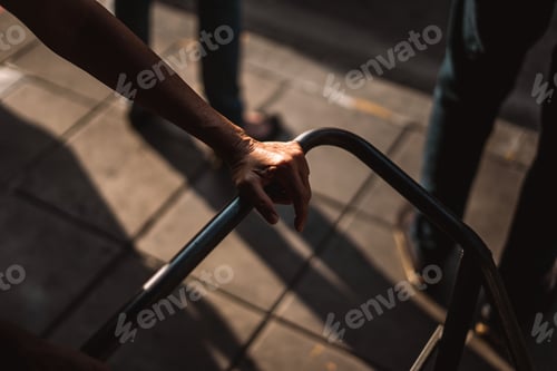 Preview: an individual's hand reaches for the bars of an outdoor railing