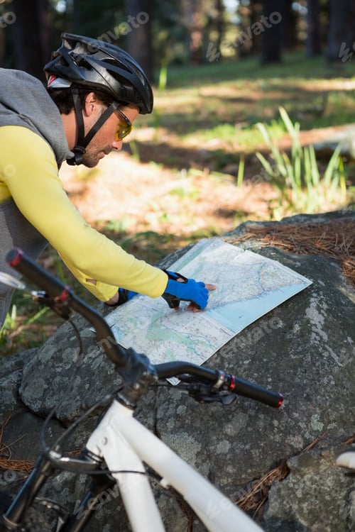 Preview: Mountain Biker Looking At Map In The Forest