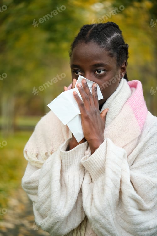 Preview: African woman blowing nose into tissue during winter. Flu.