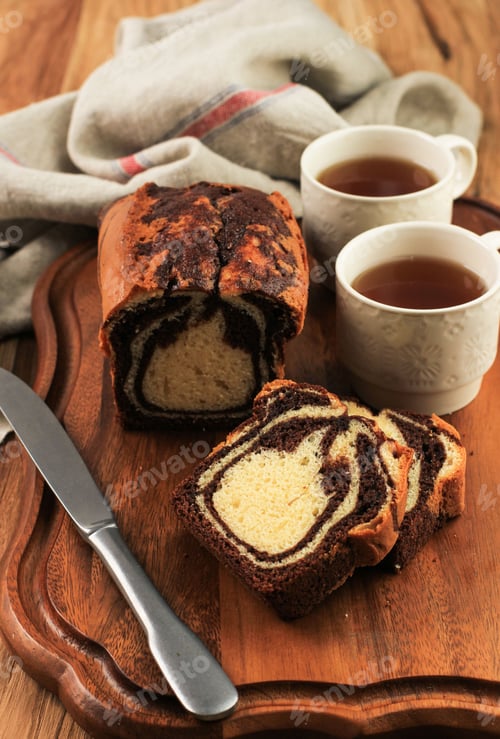 Preview: Slice of Marble Loaf Cake on Wooden Plate, Served with Cup of Tea
