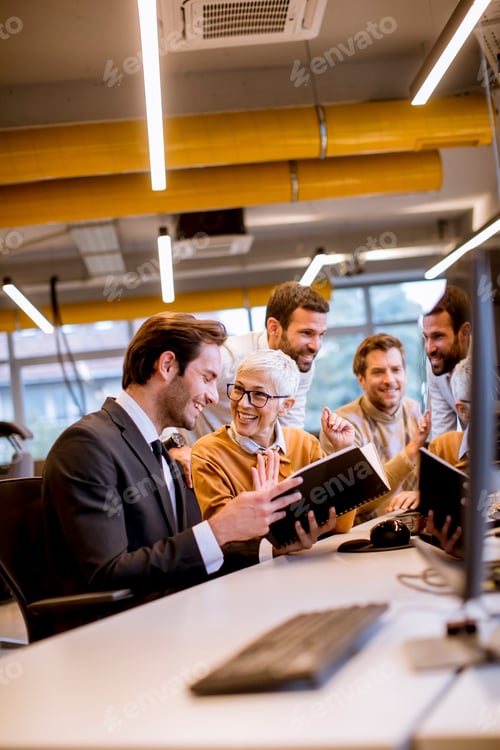 Preview: Senior businesswoman working together with young business people in modern office