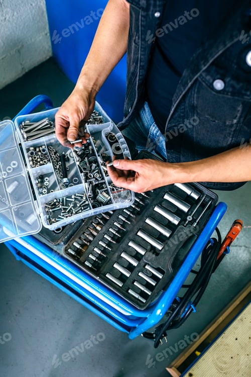 Preview: Mechanic's hands choosing screws from a tool box