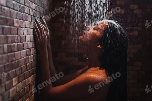 Preview: Woman relaxing under hot shower in dark room