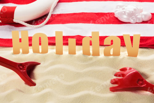 Preview: Beach toys and towel with Holiday inscription on sandy beach