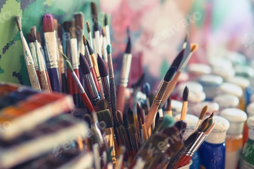 Preview: Paint brushes and watercolor paints on the table in a workshop, selective focus, close up.
