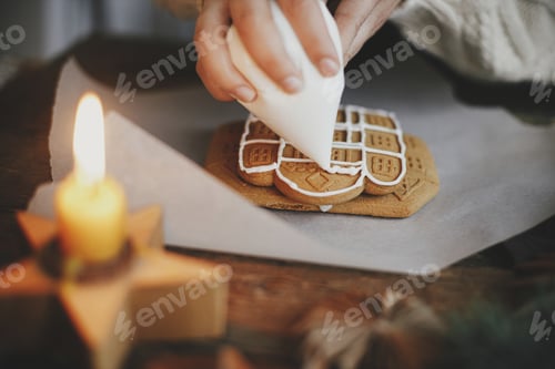 Preview: Hands decorating christmas gingerbread cookies with icing on rustic table. Atmospheric time
