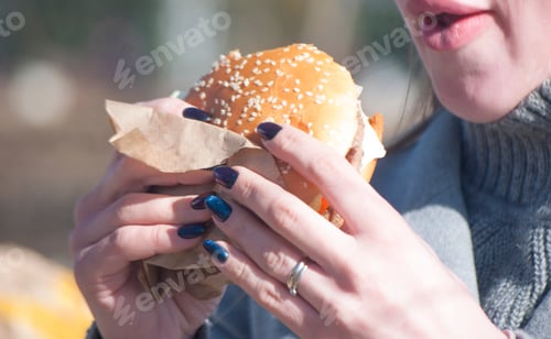 Preview: young girl eating a fresh and delicious burger