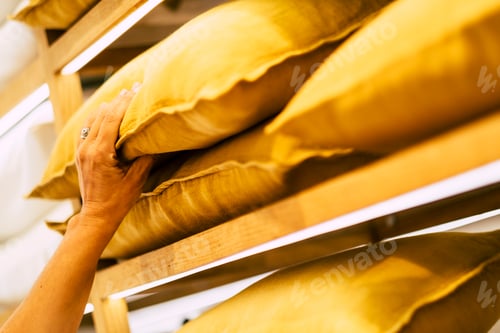 Preview: Close up of caucasian woman hand choose and take yellow pillow from a home store
