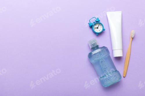 Preview: Mouthwash and other oral hygiene products on colored table top view with copy space