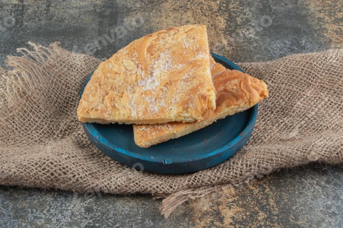 Preview: Triangle pastry with sugar on a blue plate