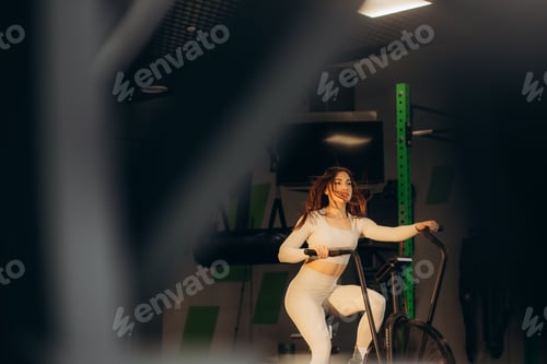 Preview: Attractive young woman at the gym riding on spinning bike. Healthy Lifestyle and Sport Concepts.