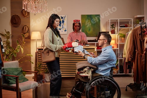 Preview: Caucasian Man with Disability Buying Second Hand Clothes with Young Asian Woman