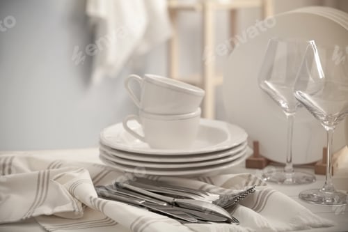 Preview: Set of clean dishware, cutlery and wineglasses on white table indoors