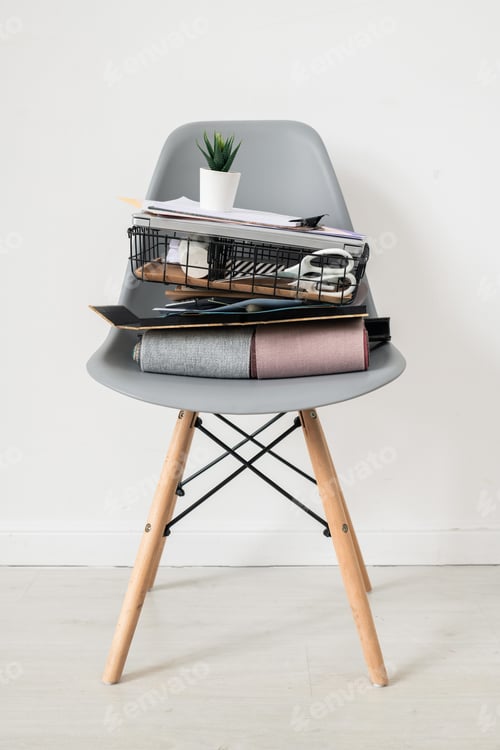Preview: Grey chair with stack of office supplies or stuff of designer of interior