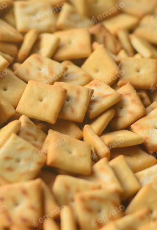Preview: A lot of small cookies are square shaped. A pattern of a yellow salt cracker