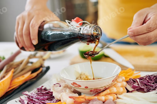 Preview: Woman pouring soy sauce into small bowl
