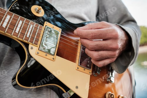 Preview: Musician playing electric guitar outdoors, close-up on hands and instrument