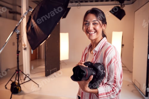 Preview: Portrait Of Smiling Female Photographer Standing In Studio With Camera And Lighting Equipment
