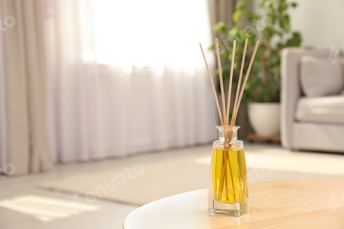 Preview: Reed air freshener with essential oil on table in room. Space for text