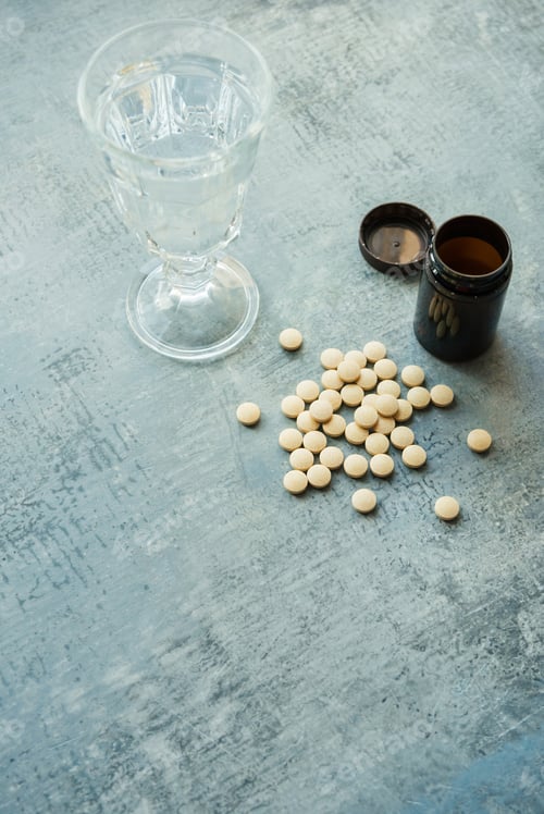 Preview: yellow round tablets pills vitamins, plastic bottle and glass cup