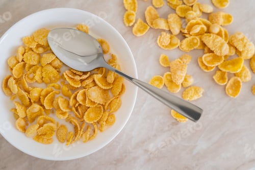 Preview: top view of bowl with corn flakes and organic milk on marble surface