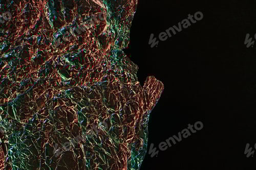 Preview: top view of glossy crumpled foil with colorful lighting reflection in darkness isolated on black