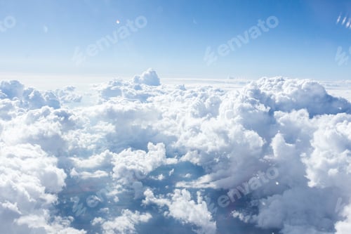 Preview: Vast expanse of fluffy clouds illuminated by the midday sun during a clear sky above