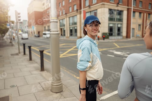 Preview: Two sportive young female friends walking city after morning running. Blurred background