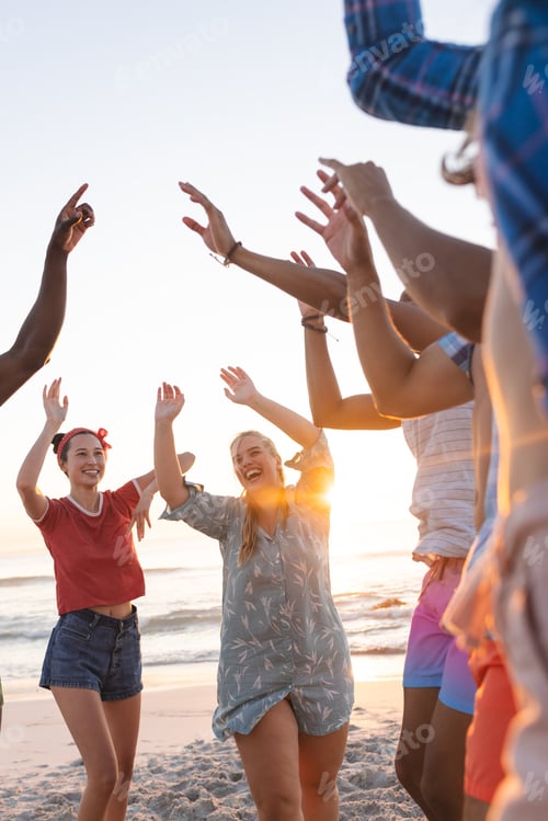 Preview: Diverse young friends enjoy a beach party at sunset, with copy space