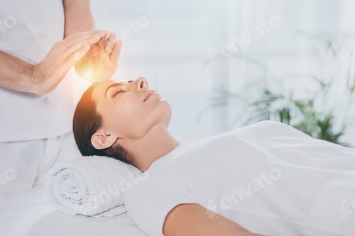 Preview: cropped shot of young woman receiving reiki therapy above head