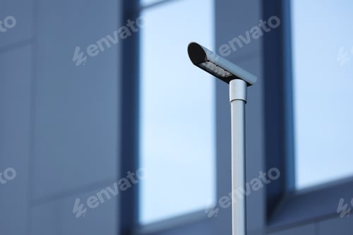 Preview: Low angle view of modern LED street lamp on urban office centre background. Led lights saving