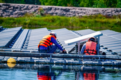 Preview: Local worker working at floating solar panels platform on the water of solar cell power plant.