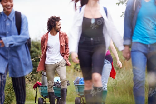 Preview: Group Of Excited Young Friends Carrying Camping Equipment Through Field To Music Festival