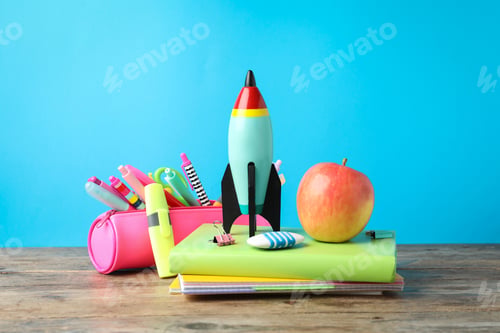 Preview: Bright toy rocket and school supplies on wooden table