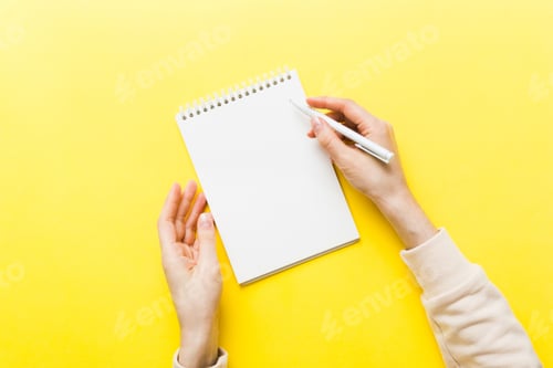Preview: Woman hand with pencil writing on notebook. Woman working on office table.