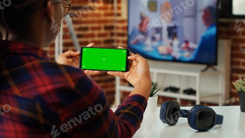 Preview: Office employee looking at horizontal greenscreen on smartphone