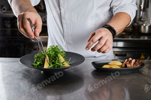 Preview: partial view of chef cooking dish with arugula, meat and potato at kitchen in restaurant
