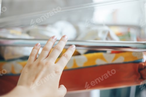 Preview: mother hand reaching to baby's bed