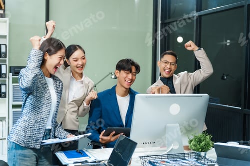 Preview: In an office, an Asian team meets at a desk, analyzing financial data on a monitor.