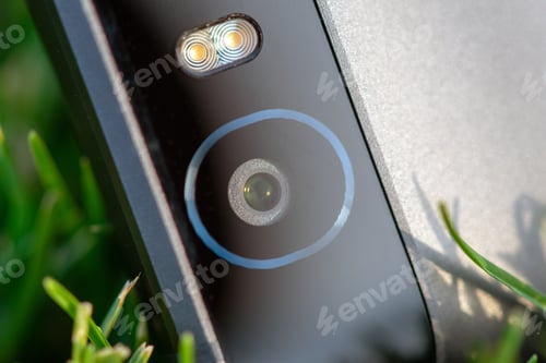 Preview: Smartphone camera with a flash close-up photo on green grass