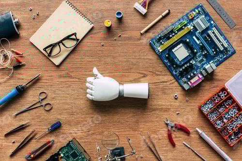 Preview: top view of prosthetic arm doing thumb up gesturing on table with tools