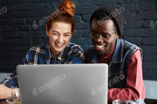 Preview: Cheerful young interracial couple enjoying high-speed wireless internet connection at coffee shop, s