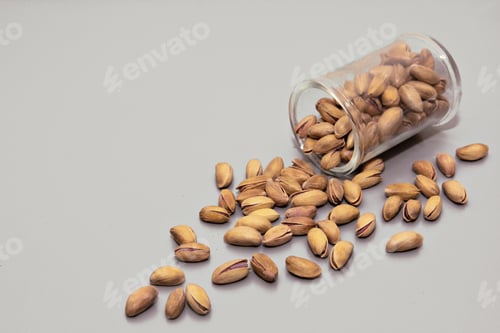 Preview: pistachio nuts in glass box on light background.