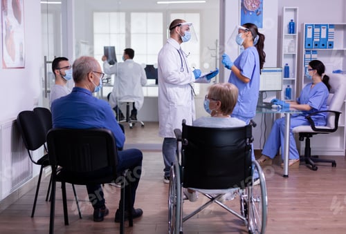 Preview: Doctor talking with nurse with face masks holding clipboard