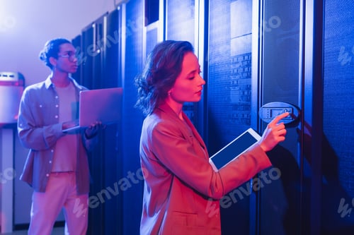 Preview: young engineer with digital tablet checking server near african american colleague with laptop