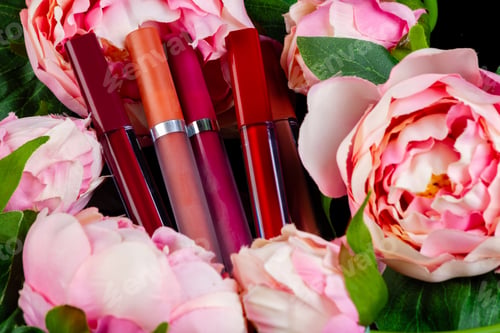 Preview: Close up lip gloss sticks and pink flowers.